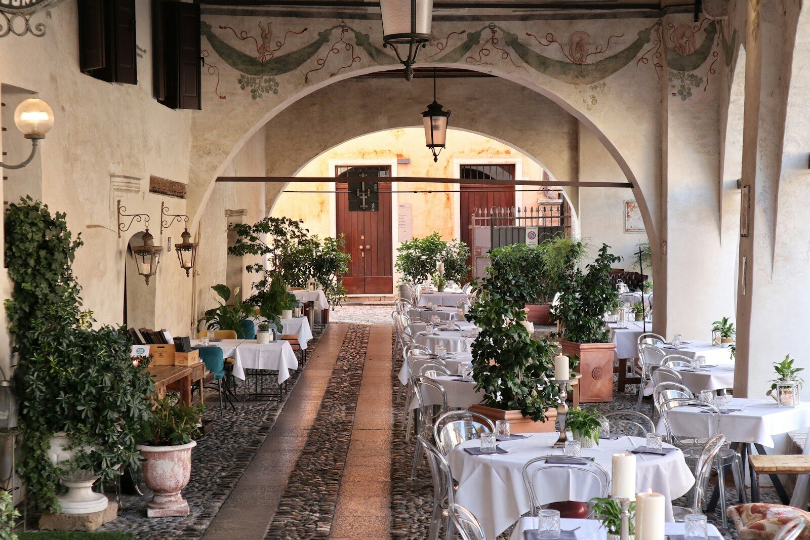 A restaurant with tables, chairs and potted plants